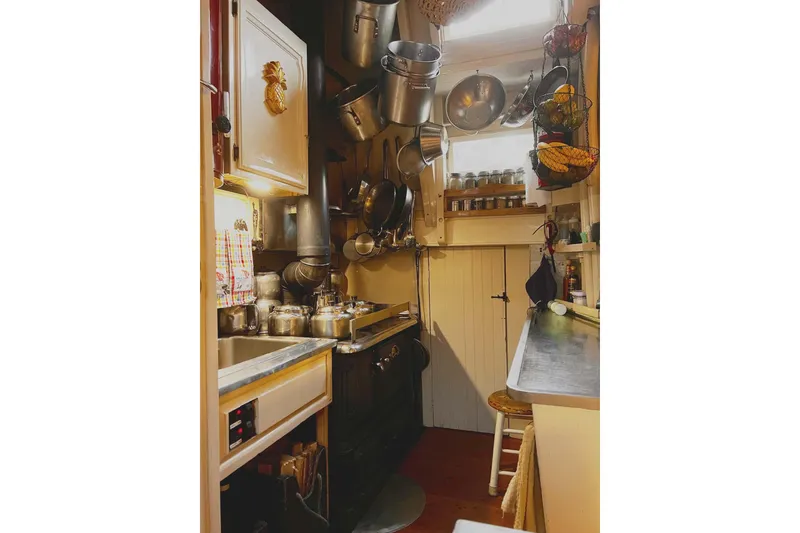 Slide: The Image of Cozy 1962 Classic Coasting Schooner kitchen with hanging pots and vintage decor. - 13