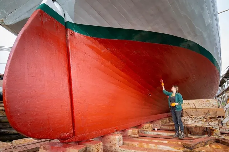 Slide: The Image of Person painting the hull of a 1962 Classic Coasting Schooner in dry dock. - 16