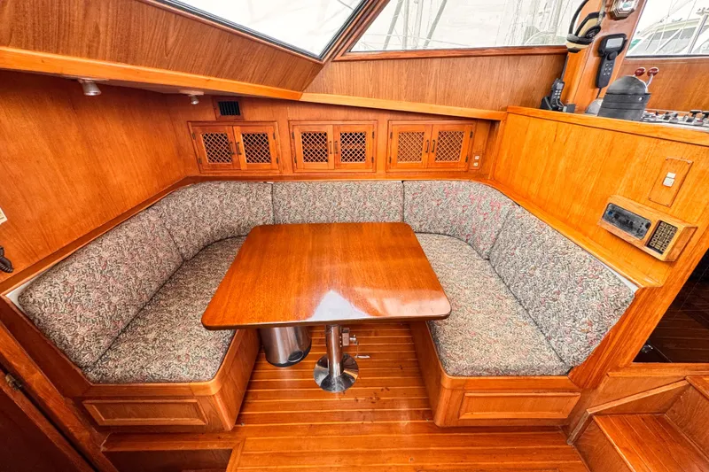 Slide: The Image of Cozy dining area in a 1985 Symbol 51 yacht with wooden table and cushioned seating. - 11
