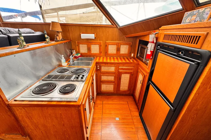Slide: The Image of Vintage 1985 Symbol 51 yacht kitchen with wood cabinetry, stove, and refrigerator. - 12