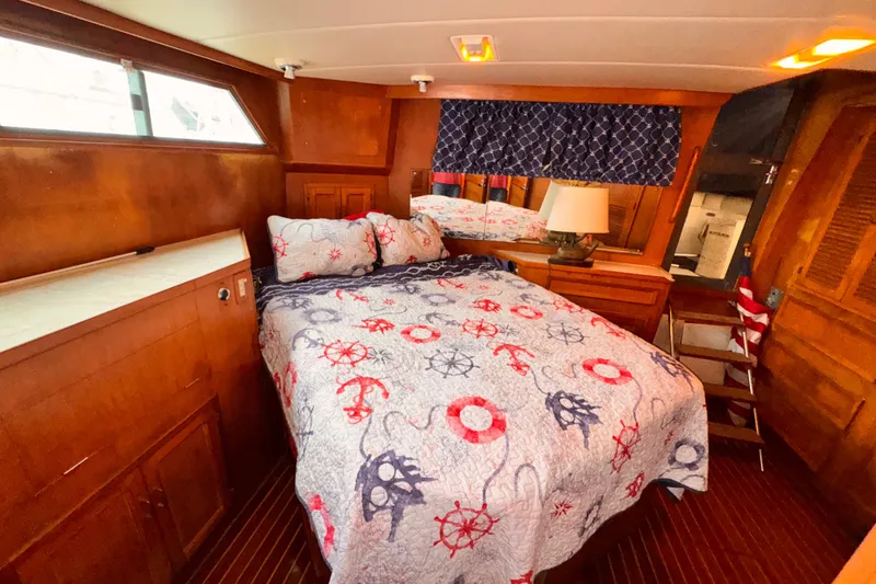 Slide: The Image of Cozy 1985 Symbol 51 yacht bedroom with nautical-themed bedding and wooden interior. - 17