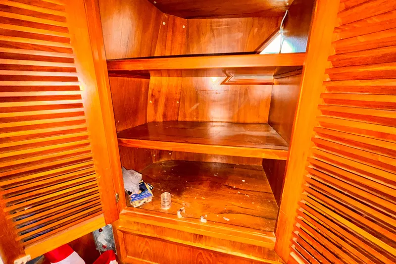 Slide: The Image of Empty wooden cabinet with open louvered doors, showing shelves and scattered items. - 20
