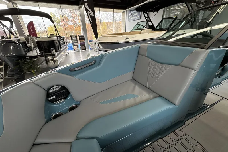 Slide: The Image of 2026 MasterCraft NXT22 boat interior with blue and gray seating in showroom. - 15
