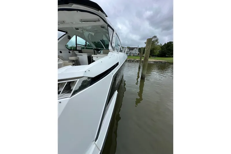 Slide: The Image of 2018 Monterey 360 Sport Coupe docked near waterfront homes under cloudy skies. - 12
