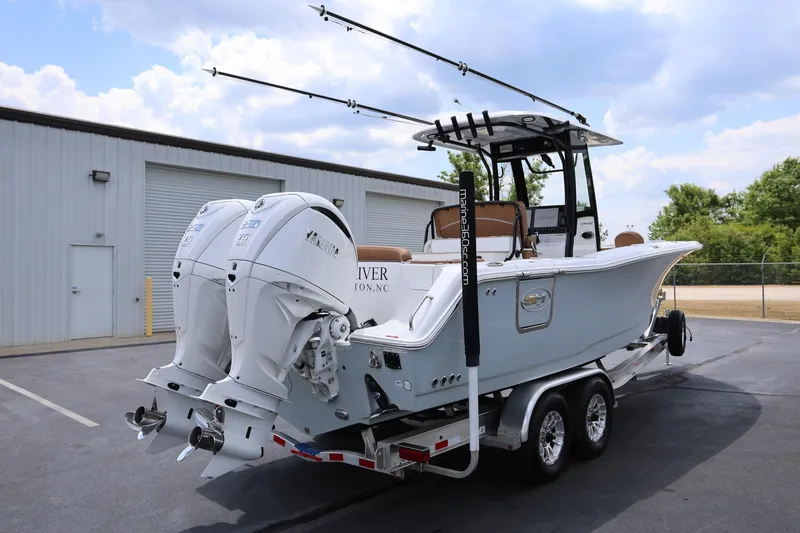 Slide: The Image of 2024 Sea Hunt Ultra 275 SE boat on trailer with dual engines, parked outdoors. - 2