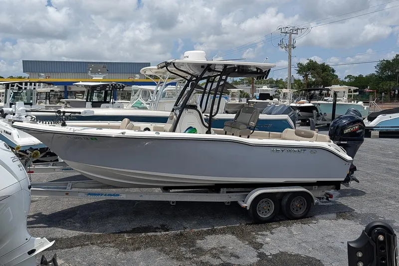 Slide: The Image of 2024 Key West 239 FS boat on trailer, parked in marina under cloudy sky. - 1