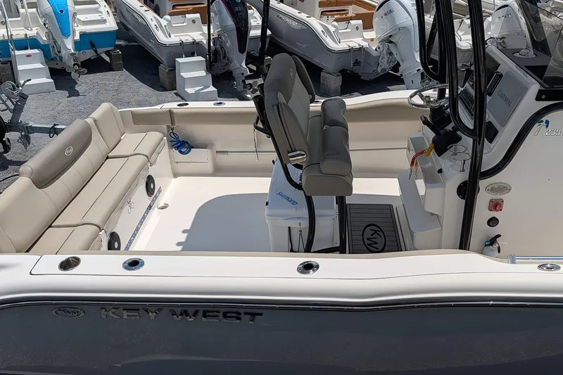 Slide: The Image of 2024 Key West 239 FS boat interior with seating and console, displayed at a marina. - 7