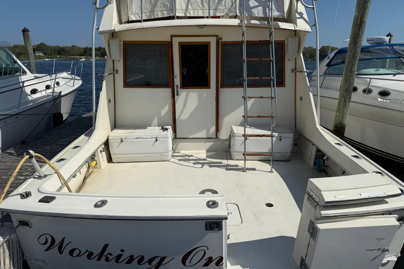 Slide: The Image of 1979 Hatteras 46 Convertible boat deck with ladder and storage, docked by the water. - 10