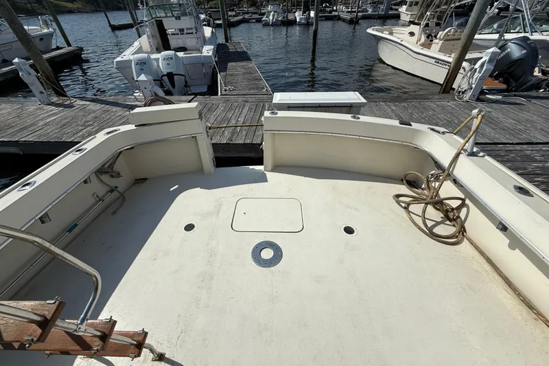 Slide: The Image of 1979 Hatteras 46 Convertible boat deck at marina, featuring spacious layout and docked vessels. - 11