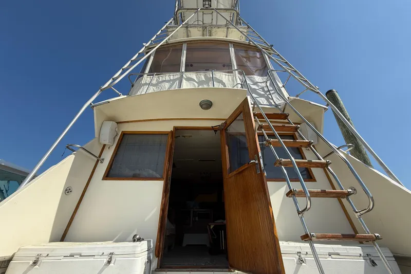 Slide: The Image of 1979 Hatteras 46 Convertible yacht with open cabin door and ladder under clear sky. - 12