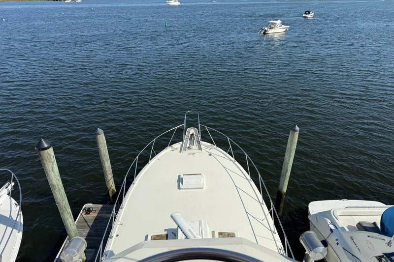 Slide: The Image of Bow view of 1979 Hatteras 46 Convertible yacht docked on calm water. - 19