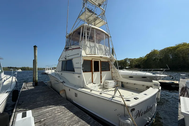 The Image of 1979 Hatteras 46 Convertible yacht docked at a marina under clear blue skies. - 2