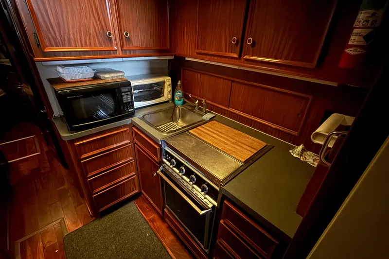 Slide: The Image of 1979 Hatteras 46 Convertible yacht kitchen with wooden cabinets, stove, and microwave. - 25