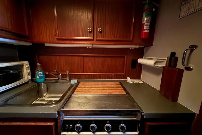 Slide: The Image of 1979 Hatteras 46 Convertible yacht kitchen with stove, sink, and wooden cabinets. - 26