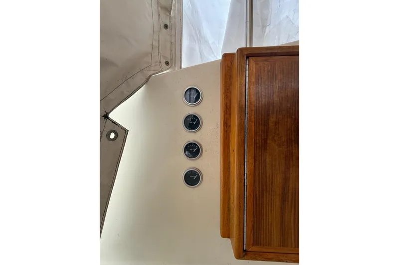 Slide: The Image of 1979 Hatteras 46 Convertible boat dashboard with four gauges and wooden panel. - 34