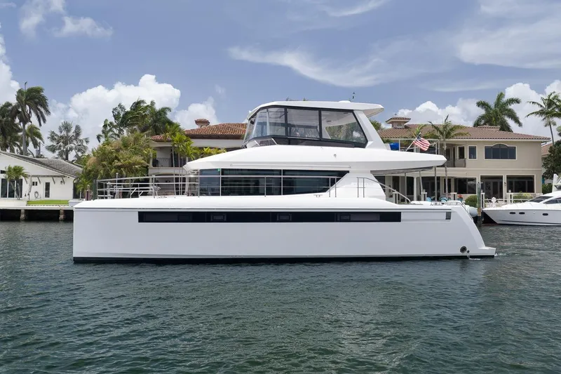 The Image of 2024 Leopard 46 Powercat yacht docked near waterfront homes, under a clear blue sky. - 0