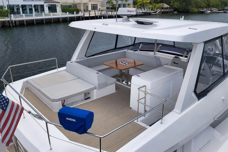 Slide: The Image of 2024 Leopard 46 Powercat yacht with spacious deck and seating area, docked by waterfront homes. - 12