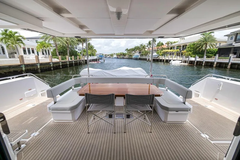 Slide: The Image of 2024 Leopard 46 Powercat yacht deck with seating and table, overlooking a scenic waterfront. - 17