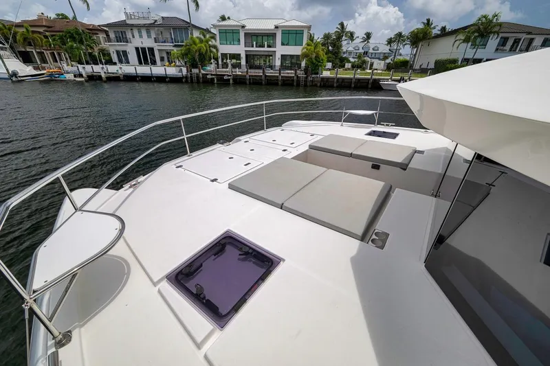 Slide: The Image of 2024 Leopard 46 Powercat yacht deck with sun loungers, docked near waterfront homes. - 26