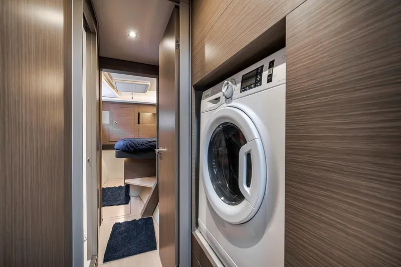 Slide: The Image of 2024 Leopard 46 Powercat interior with washer, wood paneling, and cozy bedroom view. - 68