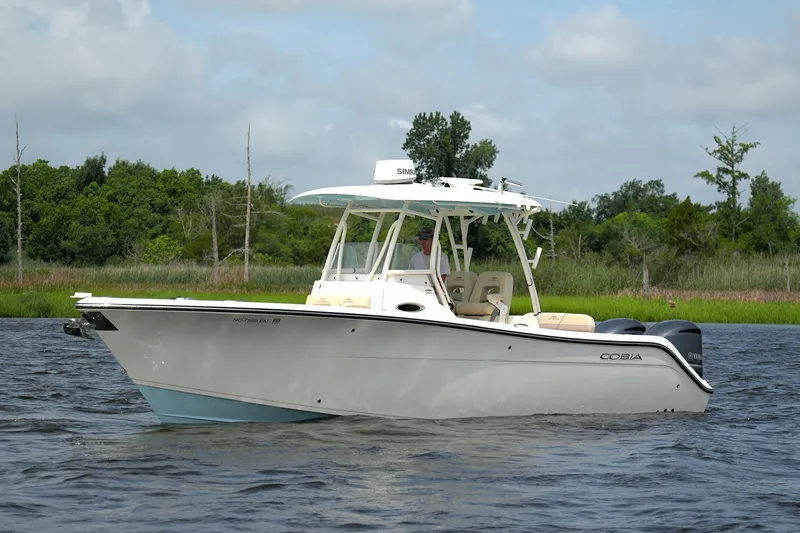 Slide: The Image of 2016 Cobia 296 Center Console boat cruising on a calm river with lush greenery. - 3