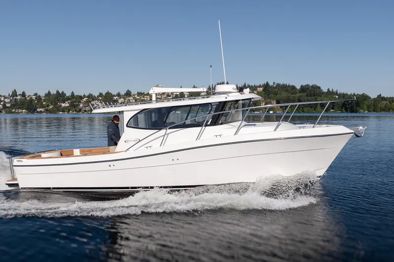 Slide: The Image of 2025 Ocean Sport Roamer cruising on a serene lake with scenic background. - 13