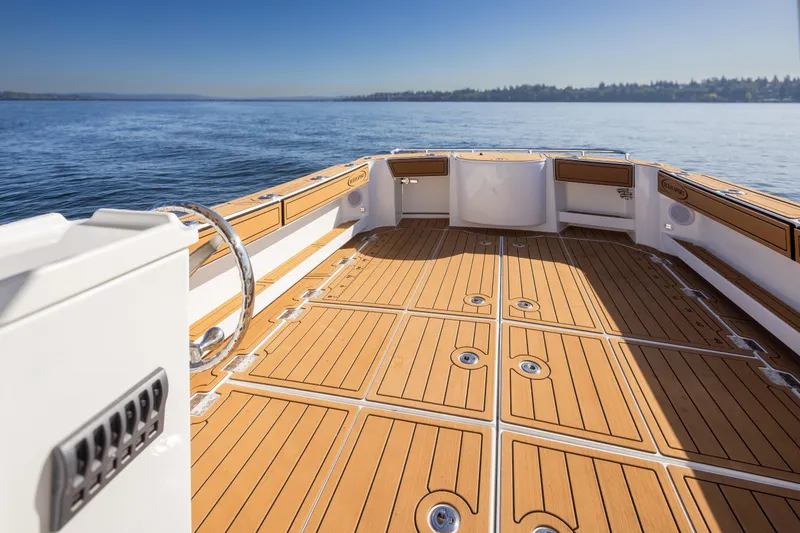 Slide: The Image of 2025 Ocean Sport Roamer boat deck with teak flooring, overlooking calm waters. - 14