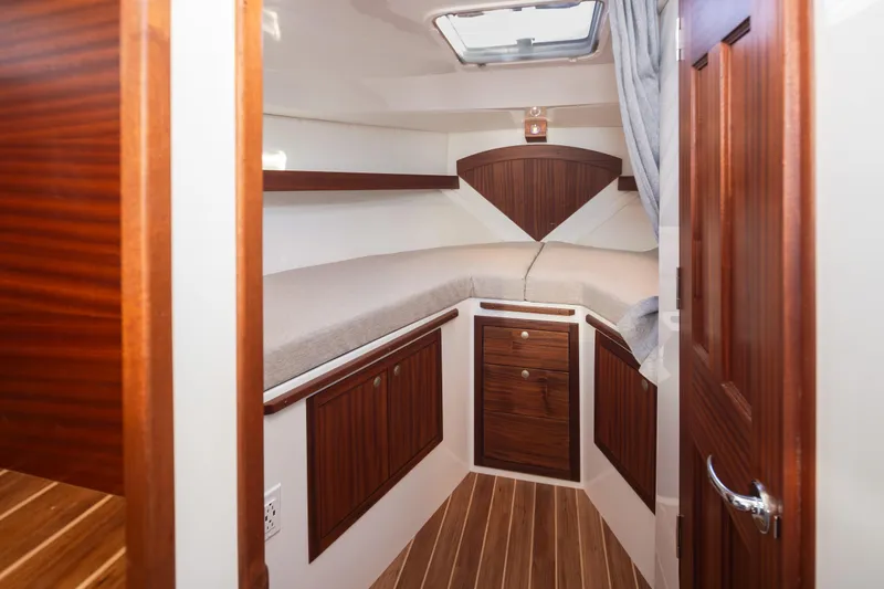 Slide: The Image of 2025 Ocean Sport Roamer cabin interior with wood paneling and cozy bed. - 33