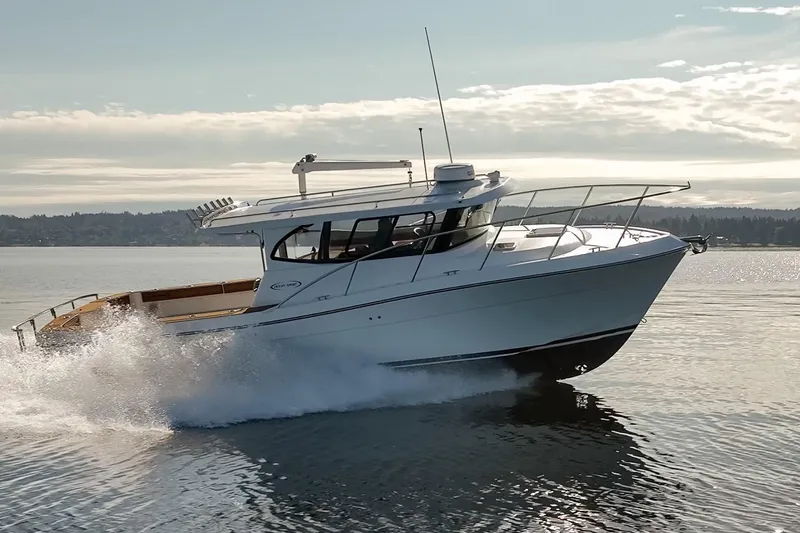 Slide: The Image of 2025 Ocean Sport Roamer cruising on a serene lake under a clear sky. - 7