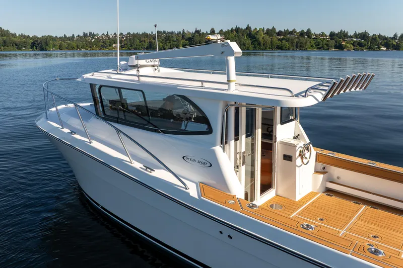 Slide: The Image of 2025 Ocean Sport Roamer boat on calm water, featuring sleek design and spacious deck. - 9