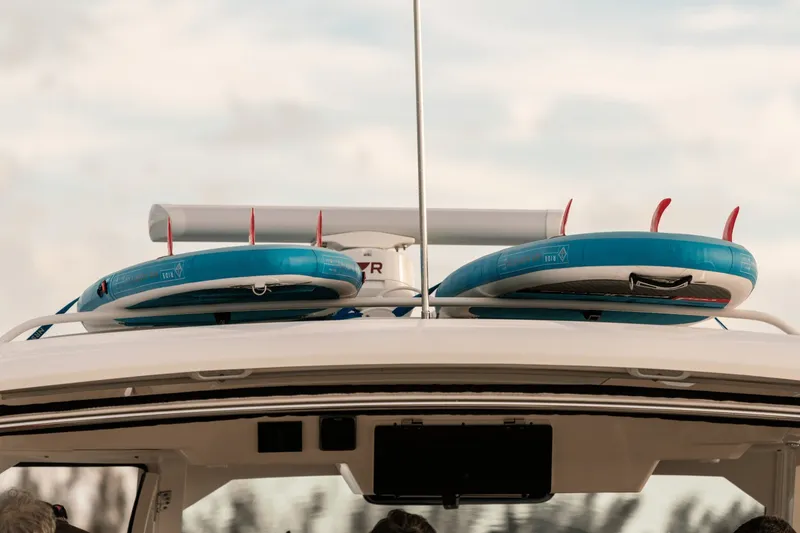 Slide: The Image of Two blue paddleboards are mounted on the roof of a 2027 Boston Whaler 380 Realm. - 45