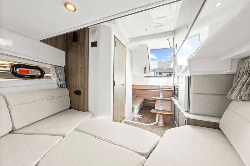 Slide: The Image of Interior of a modern yacht with beige sofas, wood accents, and a small dining table. - 45