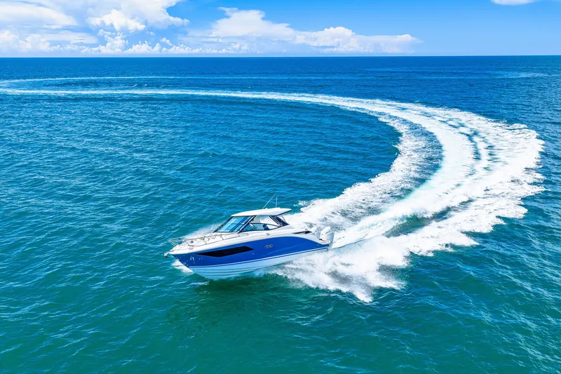 Slide: The Image of A 2027 Sea Ray Sundancer 320 Outboard speeds across the blue sea, leaving a white wake. - 15