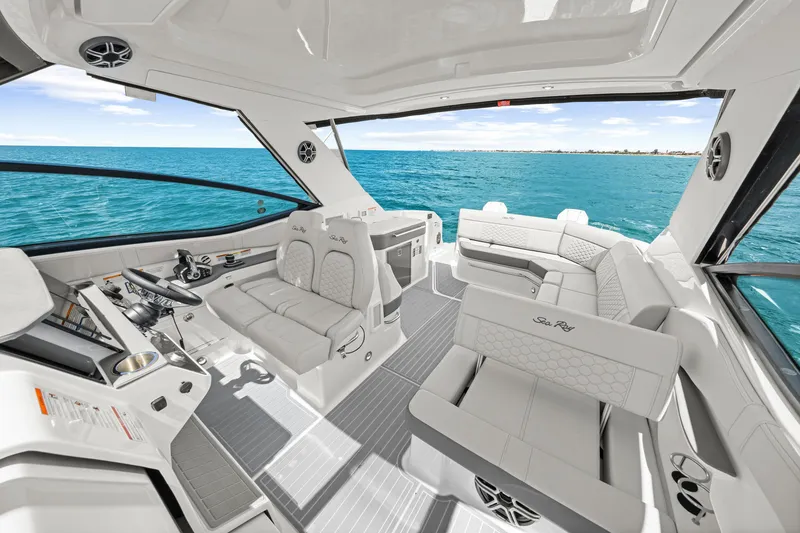 Slide: The Image of The image shows the cockpit of a 2027 Sea Ray Sundancer 320 Outboard. It features luxurious white seating and a modern helm overlooking the open sea. - 36