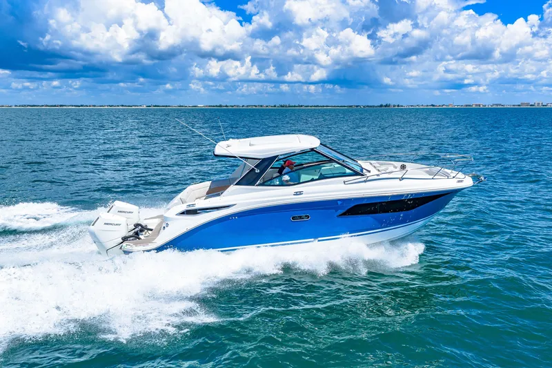 Slide: The Image of A 2027 Sea Ray Sundancer 320 Outboard speeds across blue water under a cloudy sky. - 18