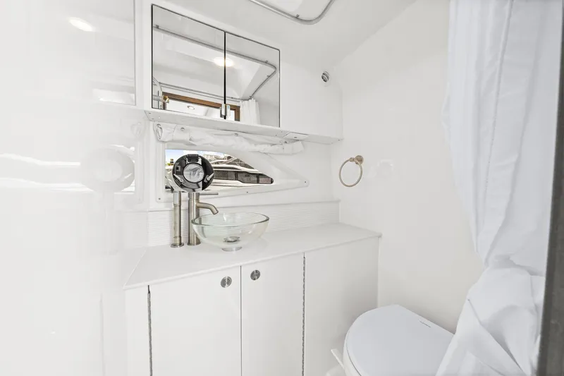 Slide: The Image of The image shows a modern boat bathroom with white interior and a glass sink. - 47