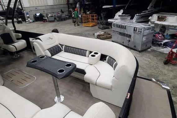 Slide: The Image of 2018 Bennington 23 GCWA pontoon boat interior with white seating and table in a workshop. - 11