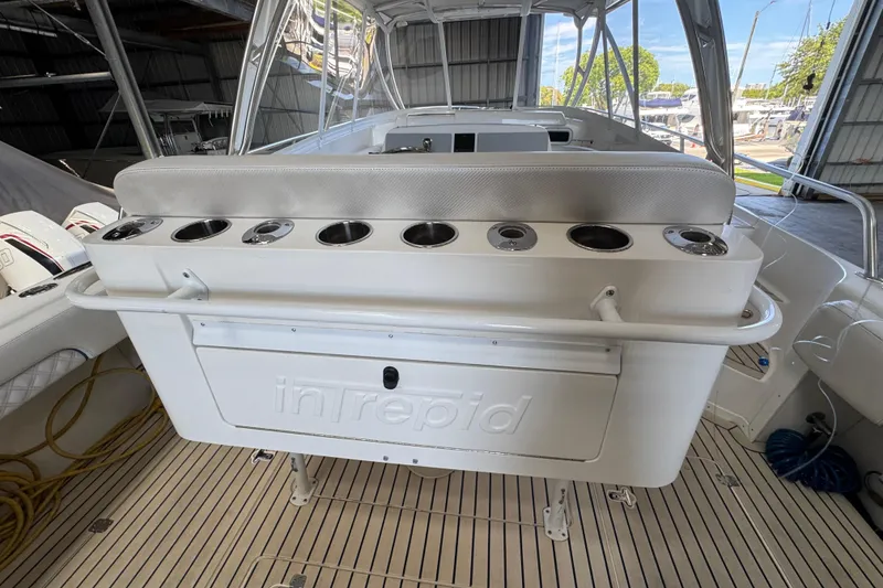 Slide: The Image of 2006 Intrepid 377 Walkaround boat interior with rod holders and storage, docked in a marina. - 15