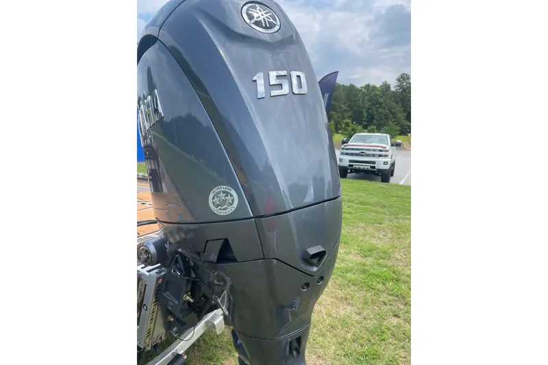 Slide: The Image of Outboard motor on Avid 20 Rogue CC 2026 boat, parked on grass with truck in background. - 16