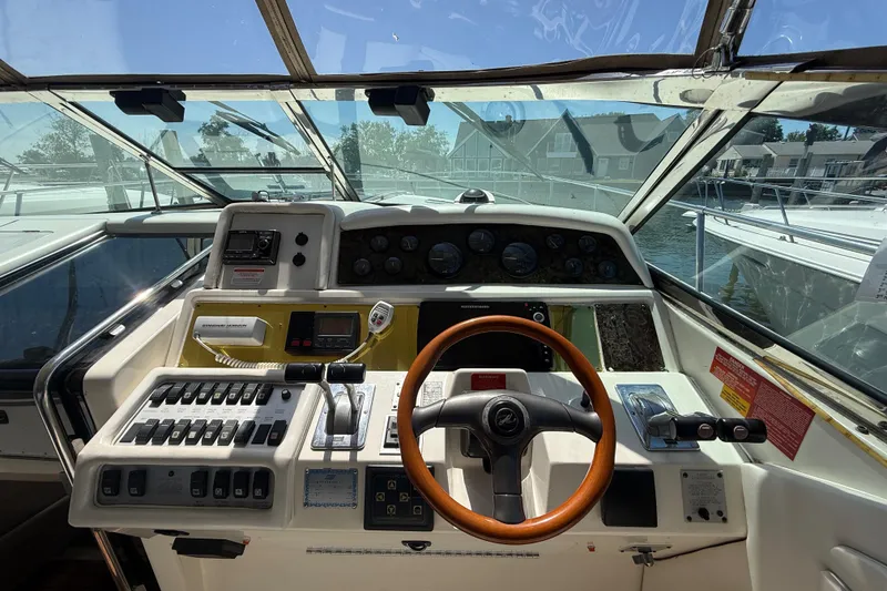 Slide: The Image of 1996 Sea Ray 400 Express Cruiser helm with controls and steering wheel, docked at marina. - 19
