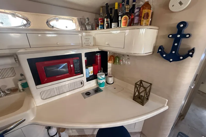 Slide: The Image of 1996 Sea Ray 400 Express Cruiser galley with red microwave, bar setup, and nautical decor. - 30