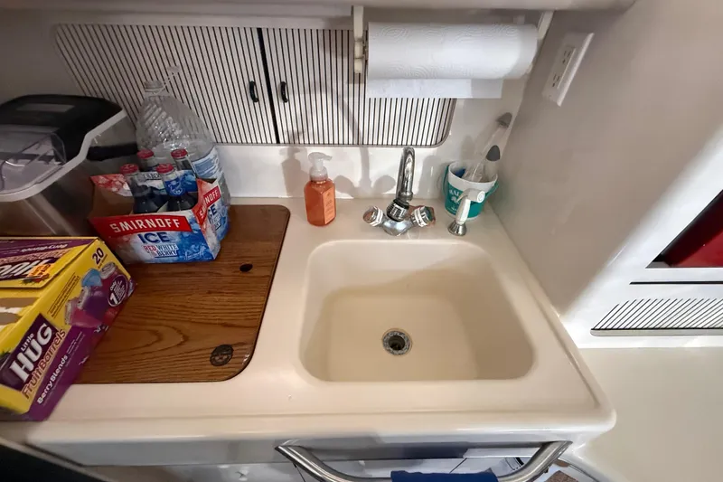 Slide: The Image of 1996 Sea Ray 400 Express Cruiser kitchen sink with beverages and cleaning supplies. - 33