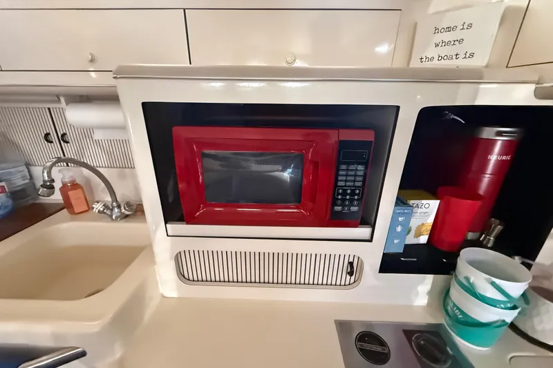 Slide: The Image of 1996 Sea Ray 400 Express Cruiser kitchen with red microwave and sink. - 34