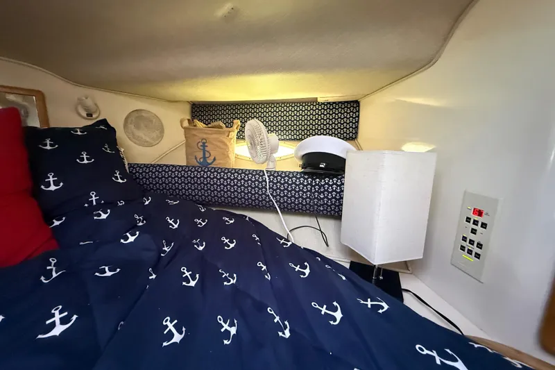 Slide: The Image of Cozy cabin interior of 1996 Sea Ray 400 Express Cruiser with nautical-themed bedding. - 48