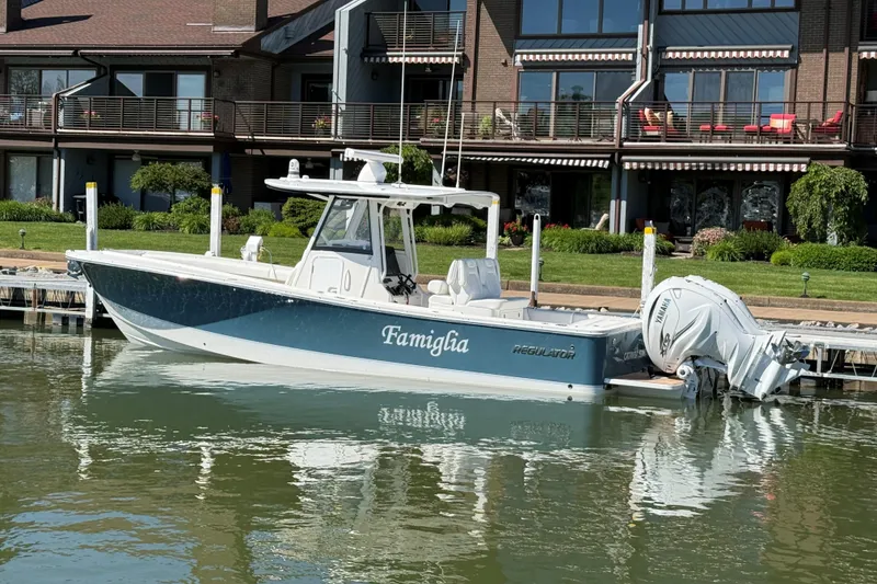 Slide: The Image of 2021 Regulator 31 boat docked by waterfront homes, featuring twin Yamaha engines. - 15