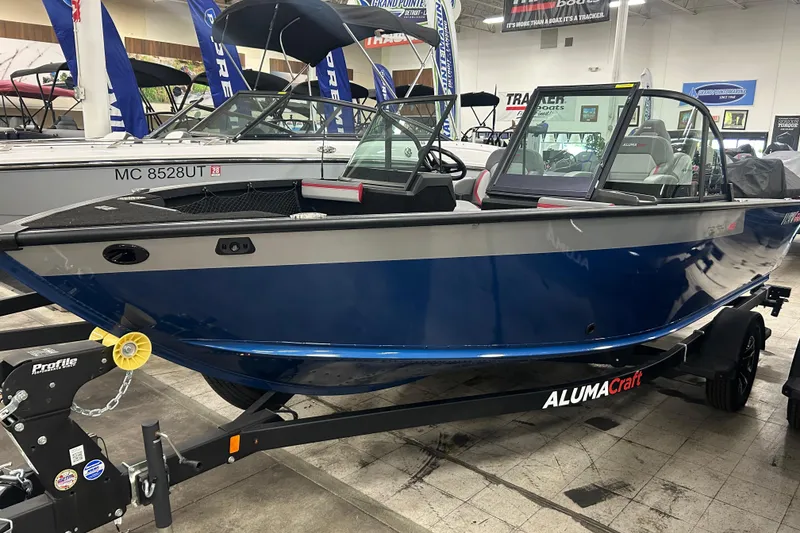 The Image of 2025 Alumacraft Trophy 185X Sport boat displayed indoors on a trailer. - 1