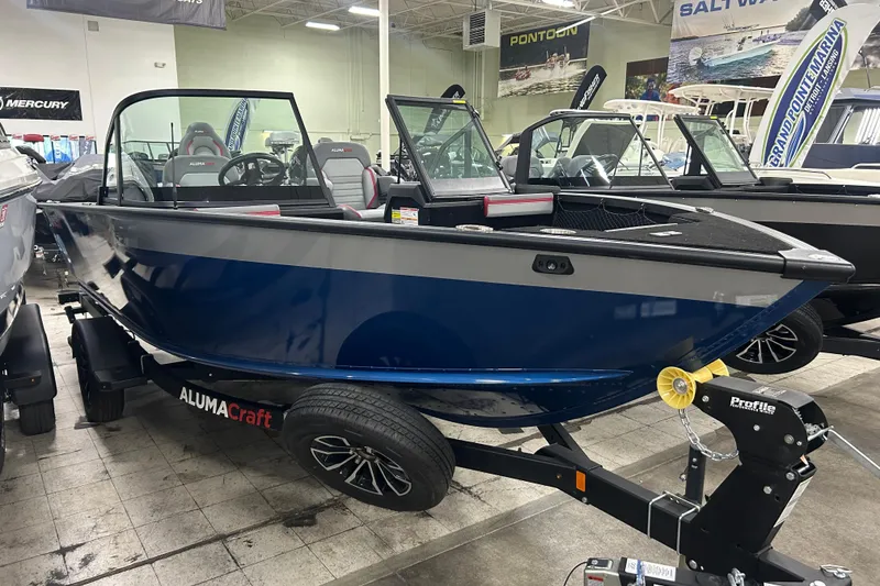 Slide: The Image of 2025 Alumacraft Trophy 185X Sport boat displayed in showroom on trailer. - 2