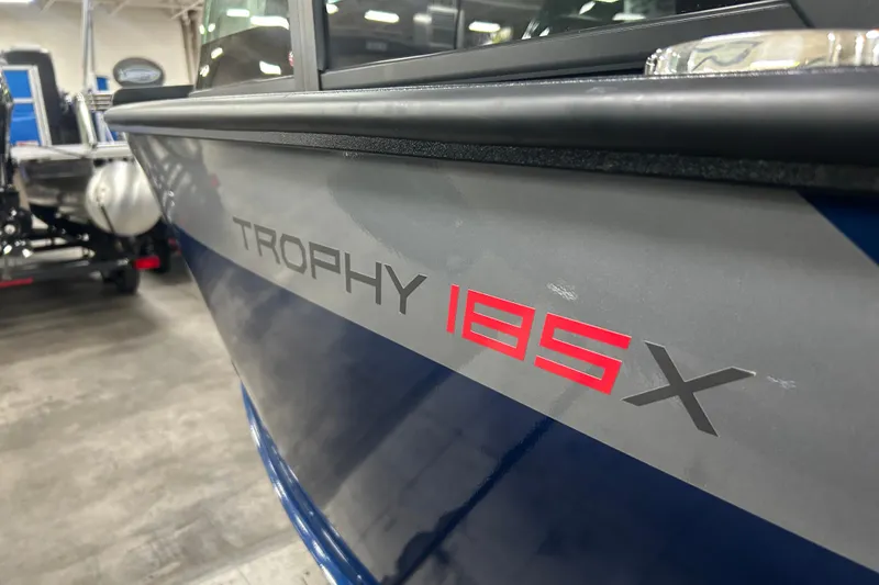 Slide: The Image of 2025 Alumacraft Trophy 185X Sport boat in showroom, close-up of model name. - 3