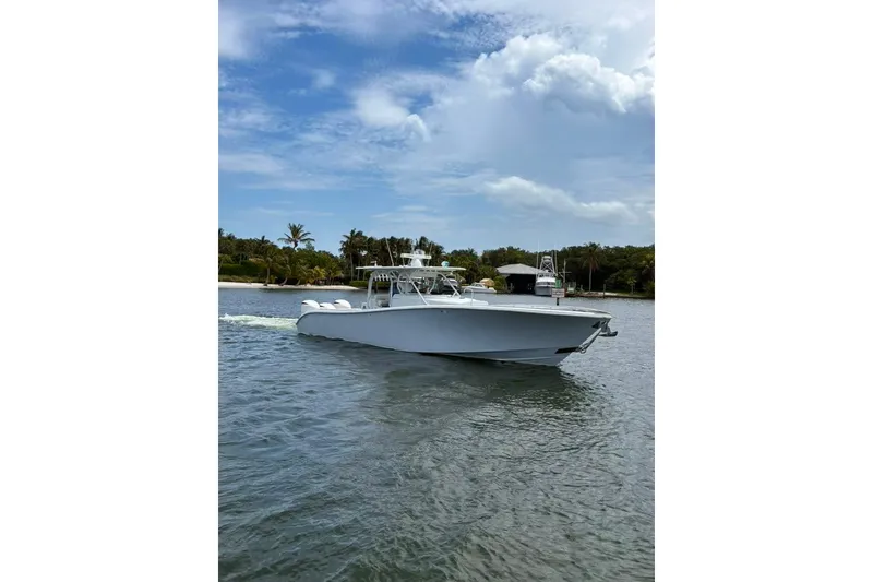 Slide: The Image of 2014 Yellowfin 42 Offshore boat cruising on a calm, scenic waterway under a partly cloudy sky. - 25