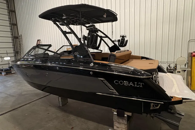 The Image of 2026 Cobalt R4 Surf boat in a warehouse, featuring sleek black design and modern amenities. - 1